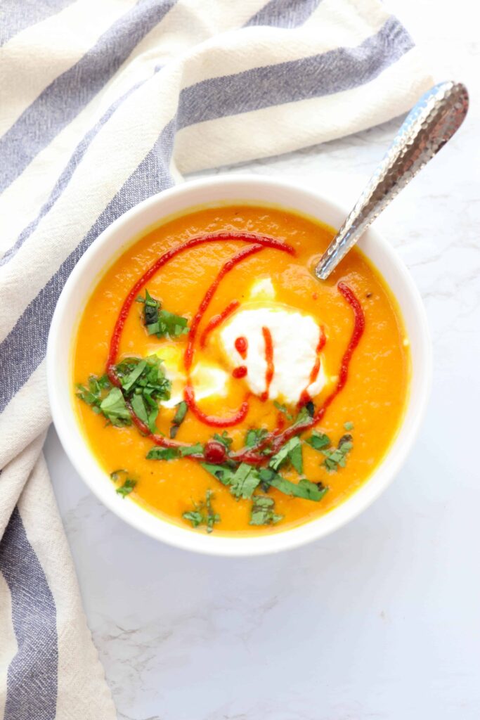 A bowl of creamy carrot soup with Greek yogurt and sriracha