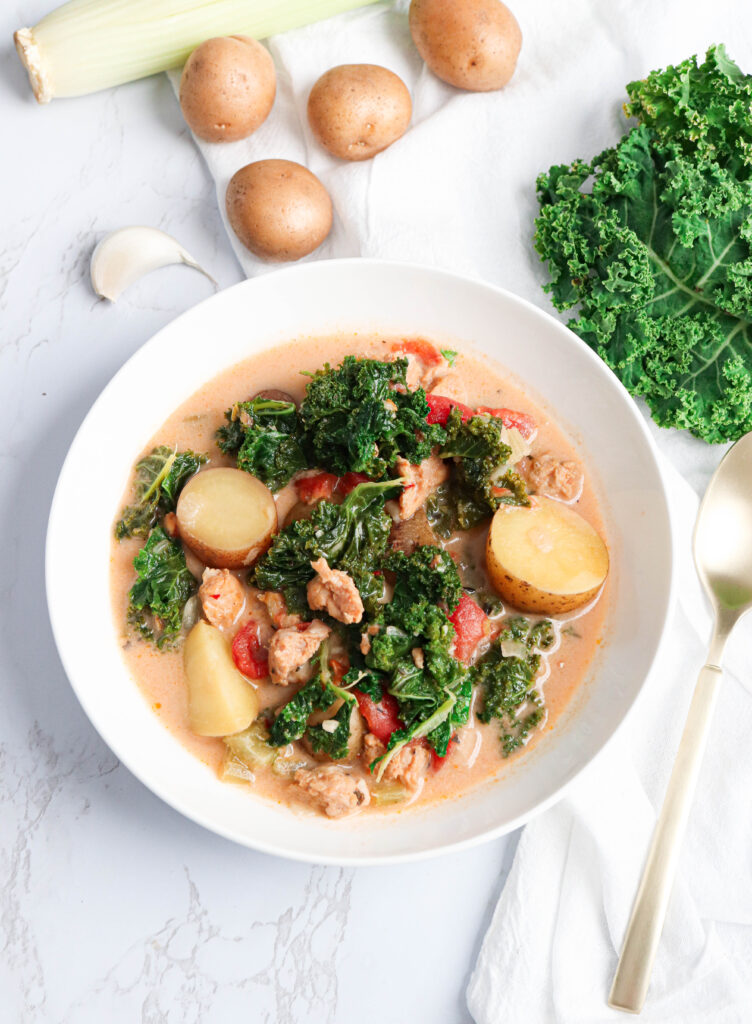 a bowl of sausage kale soup with potatoes and tomatoes