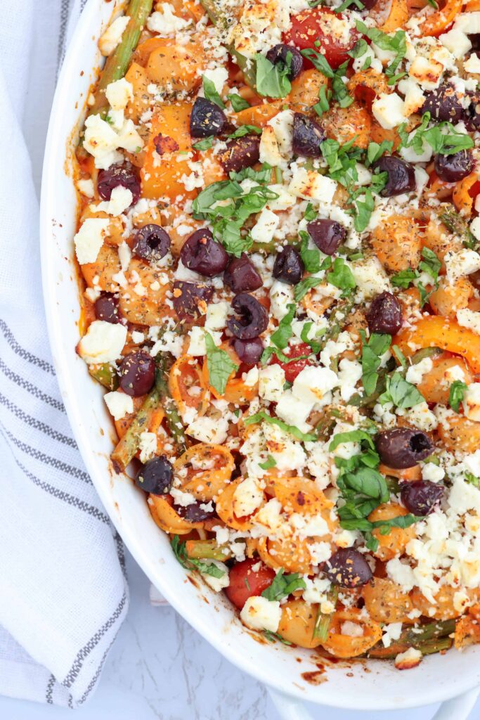 Greek chickpea pasta bake with olives and feta cheese in an oval casserole dish.