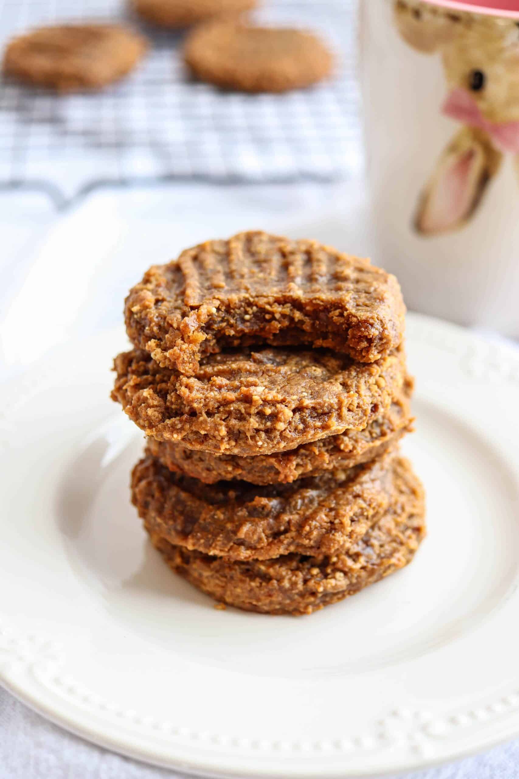 a stack of 5 peanut butter banana cookies with the top cookie bitten on a white plate