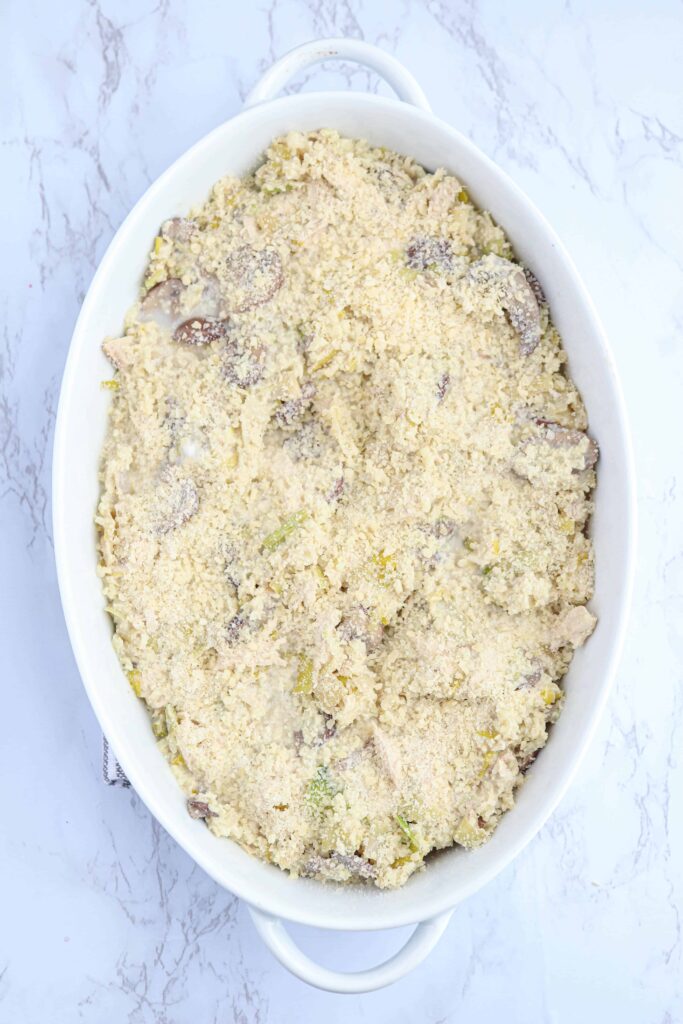 unbaked chicken and mushroom cauliflower rice casserole in a white oval casserole dish on white marble countertop