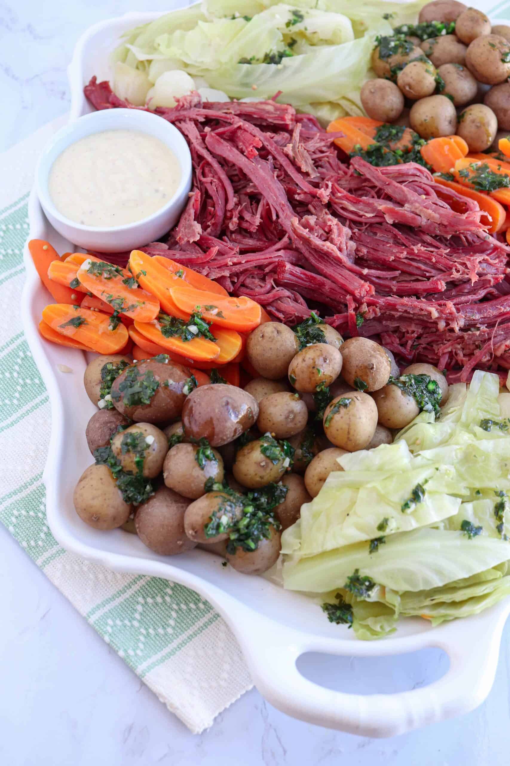 a tray with corned beef, boiled potatoes, carrots, cabbage