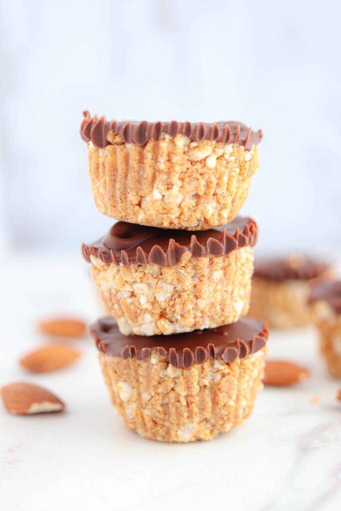 three chocolate almond butter rice cups stacked on white marble counter