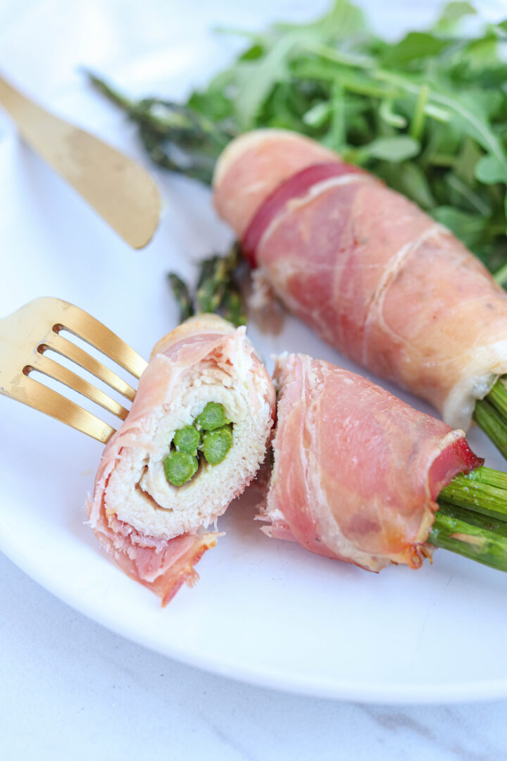 asparagus stuffed chicken wrapped in prosciutto cut in half.