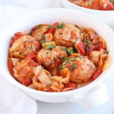 a white bowl with meatballs and cabbage in tomato sauce