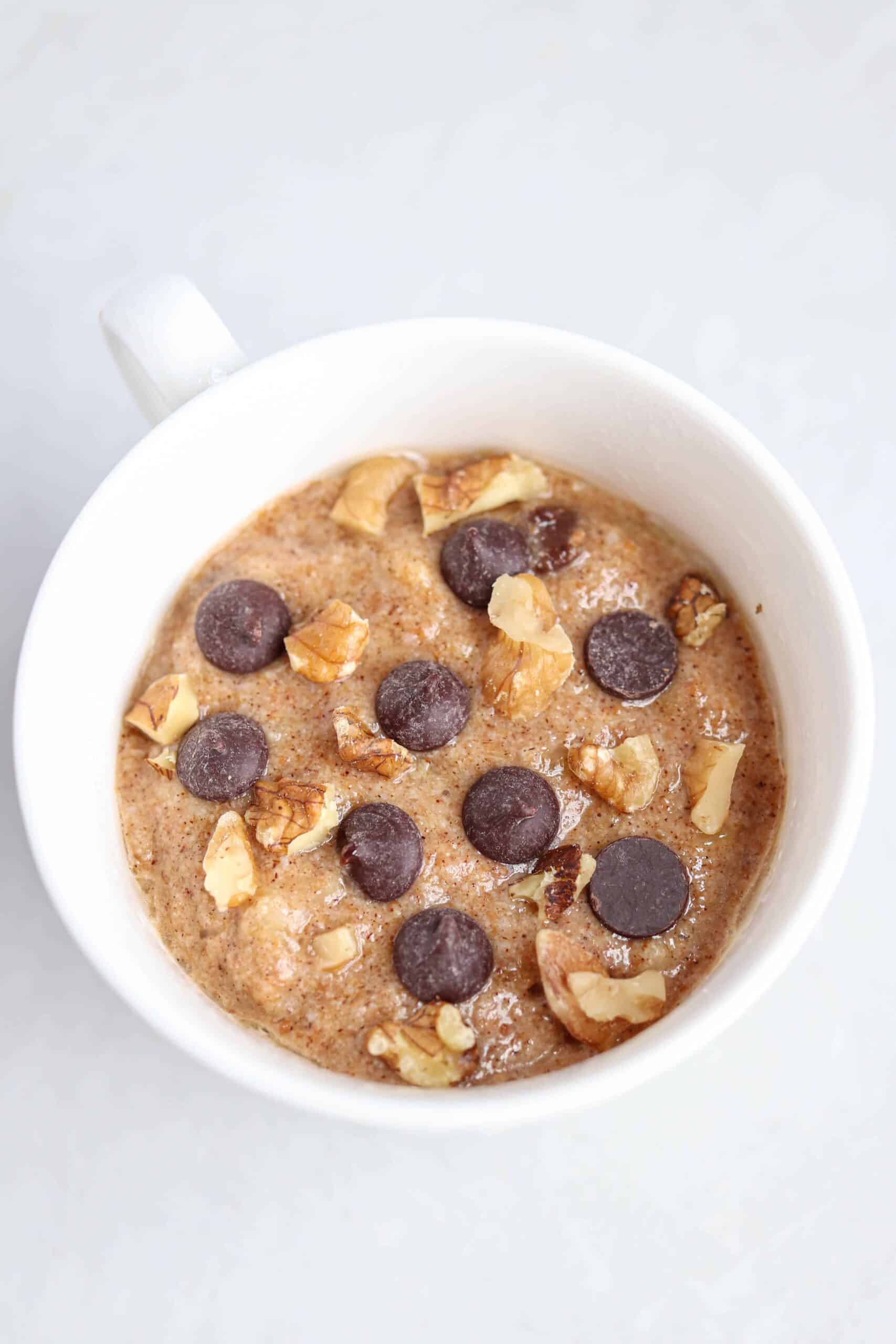 banana mug cake topped with walnuts and chocolate chips before cooking.