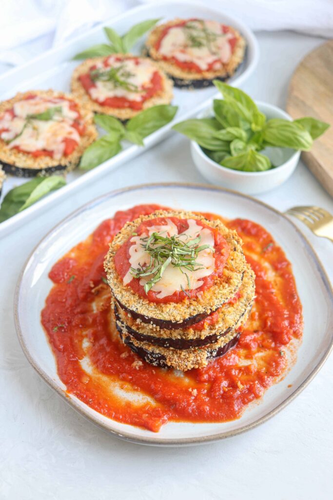 a stack of eggplant parm in tomato sauce on a gray plate.