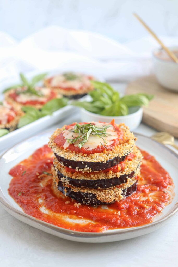 a stack of eggplant parm in tomato sauce on a gray plate.