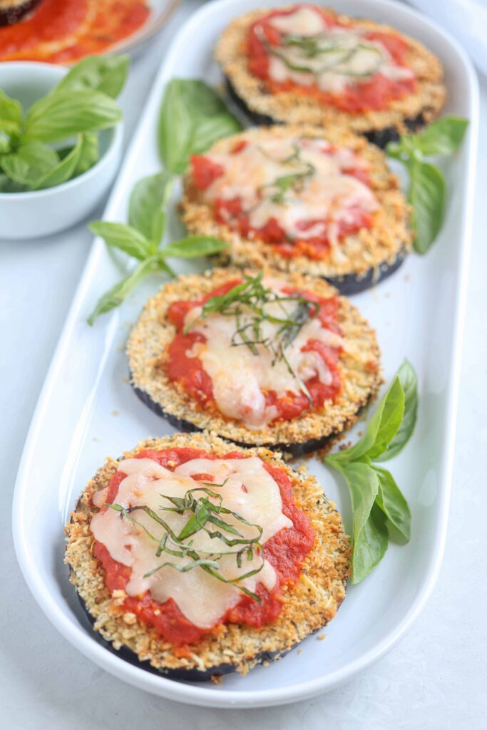 eggplant parmesan slices on a white oval plate.