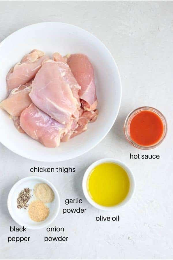 buffalo chicken thighs ingredients laid out on a light gray surface and labeled