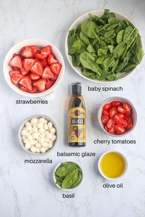 strawberry spinach caprese salad ingredients laid out on marble counter