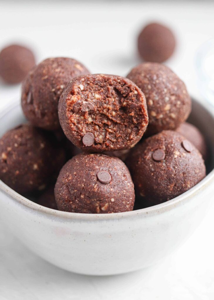 chocolate bliss balls in a small gray bowl, bite shot.