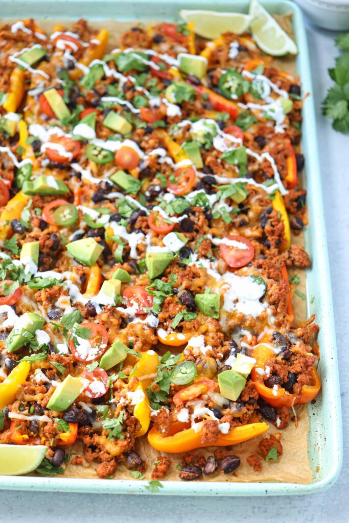 a baking sheet with mini pepper loaded nachos on light gray surface