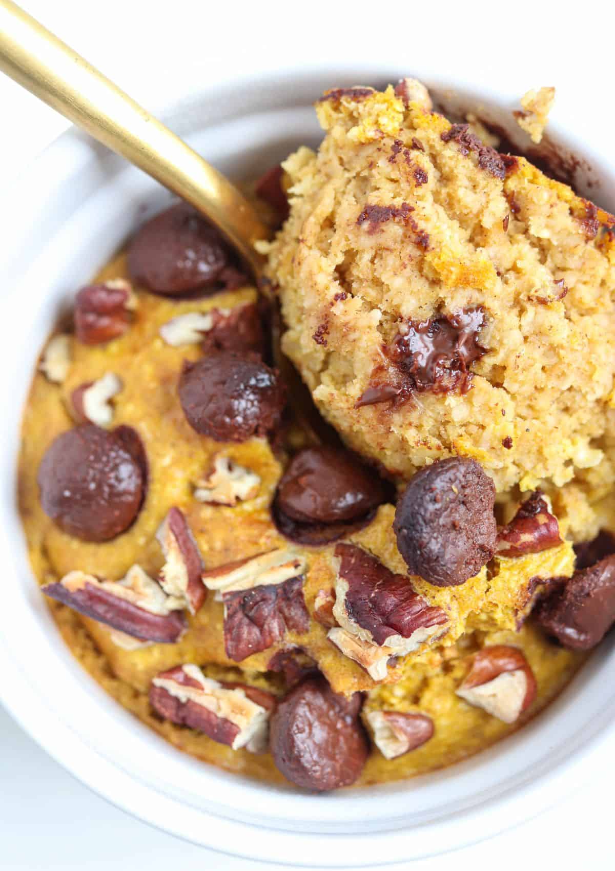 pumpkin blended baked oats in a white ramekin with chocolate chips and pecans.