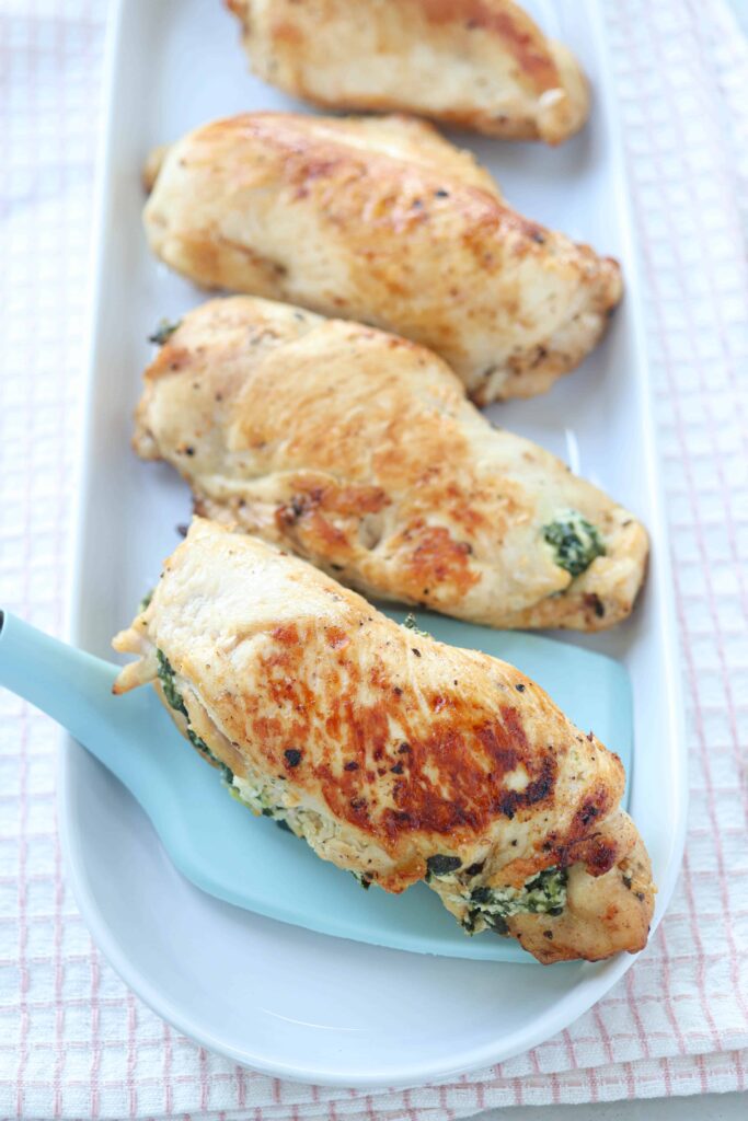 chicken breasts stuffed with spinach and cheese on an oval platter.