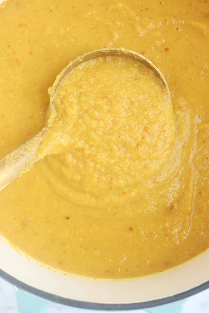 creamy pumpkin cauliflower soup in a pot with a ladle, closeup