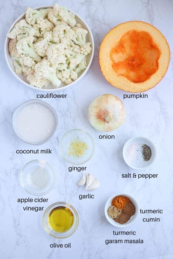 pumpkin cauliflower soup ingredients laid out in round dishes on a white marble surface