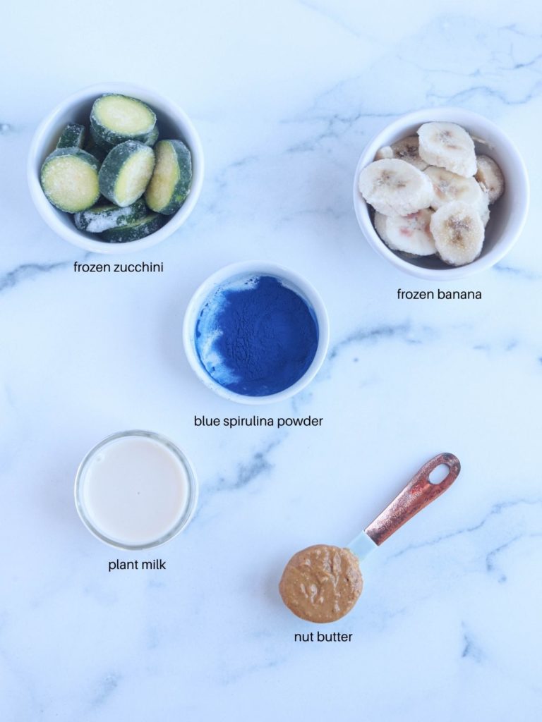 blue smoothie bowl ingredients laid out on a marble surface with captions