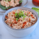 buffalo tuna salad in a small gray bowl drizzled with hot sauce and sprinkled with chives
