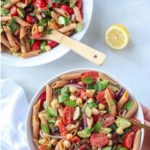 lentil pasta salad with tomatoes, cucumbers, chickpeas and herbs in a white bowl