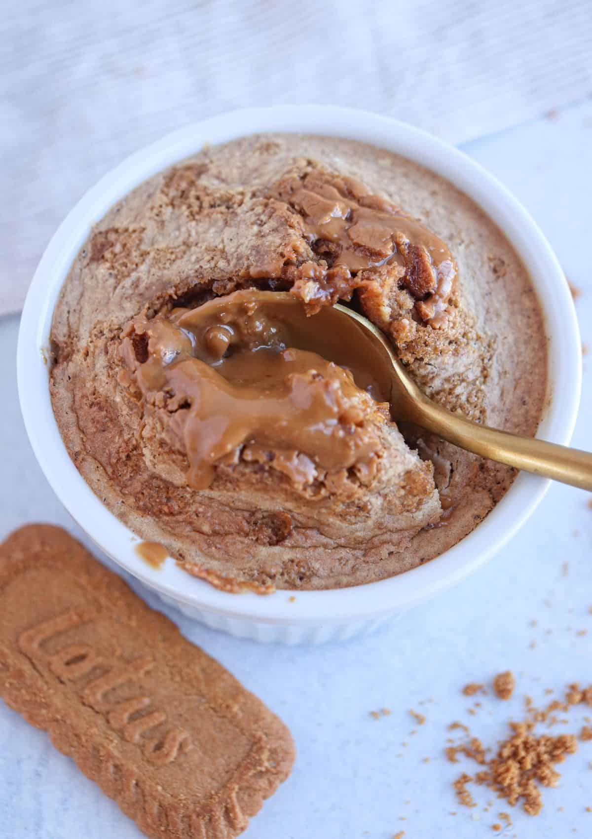 blended Biscoff baked oats in a white ramekin with a gold spoon.