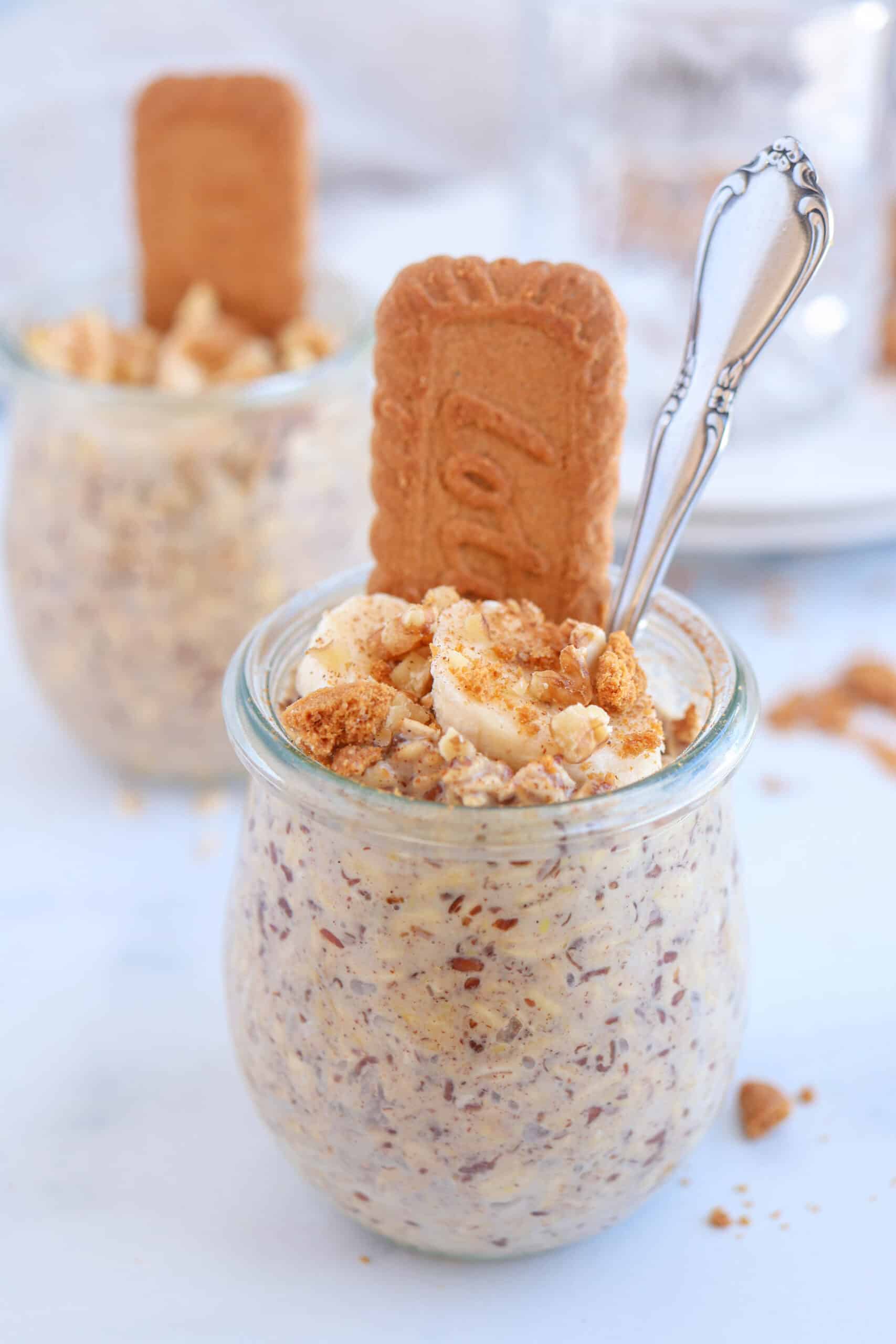 biscoff overnight oats in a tulip jar topped with sliced banana, walnuts and crushed biscoff cookies.