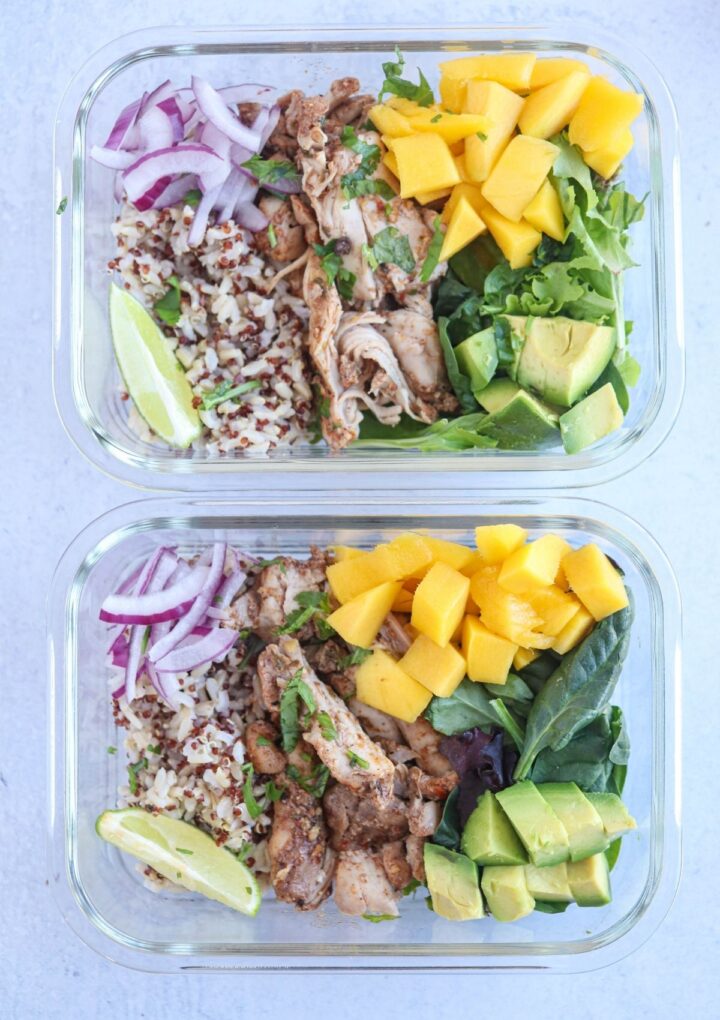 jerk chicken rice meal prep with diced mango, greens, avocado, red onions and lime in 2 glass containers.