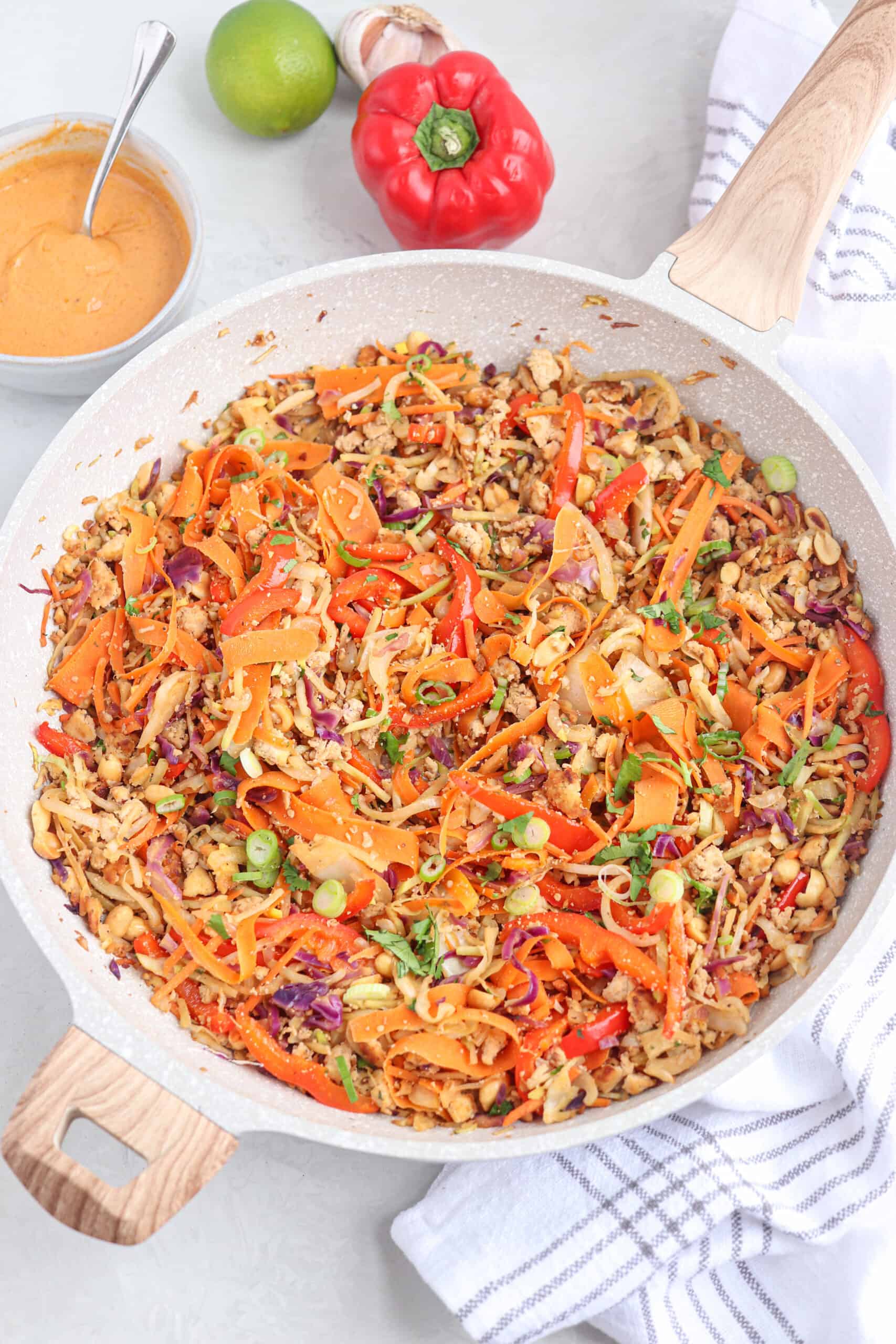 vegan egg roll in a bowl with tofu, peanuts and vegetables in a light gray skillet.