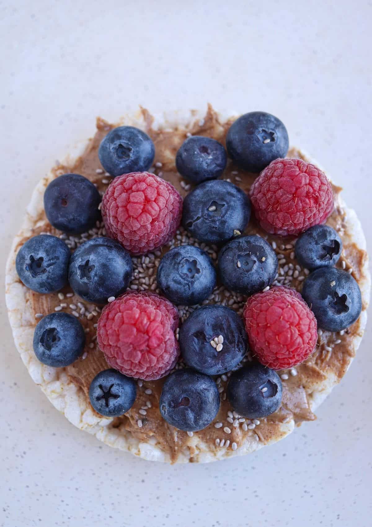 rice cake topped with almond butter and fresh berries and chia seeds.