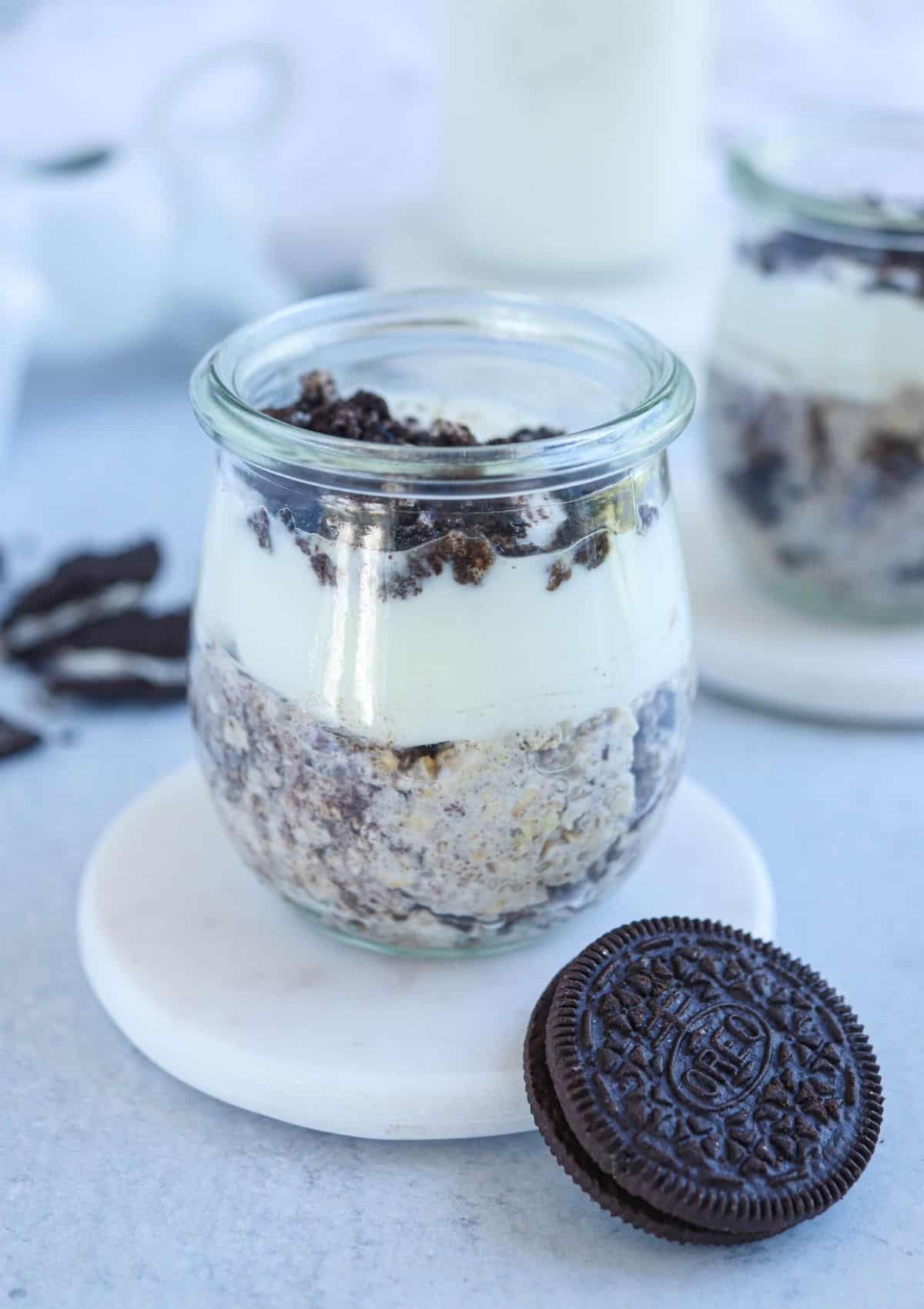 oreo overnight oats topped with yogurt and crushed oreos in a small glass jar.