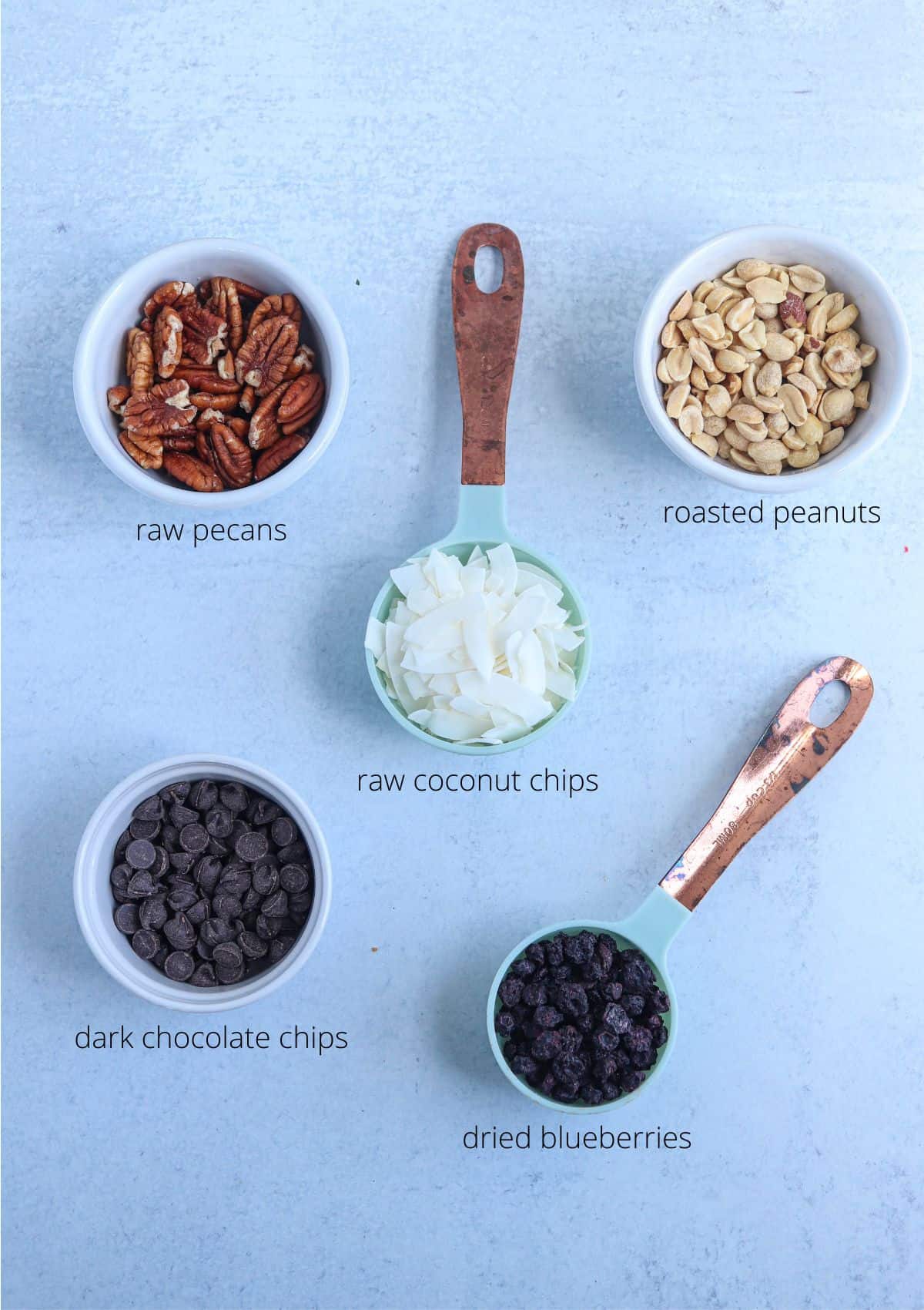 low carb trail mix ingredients in small containers on a gray surface.
