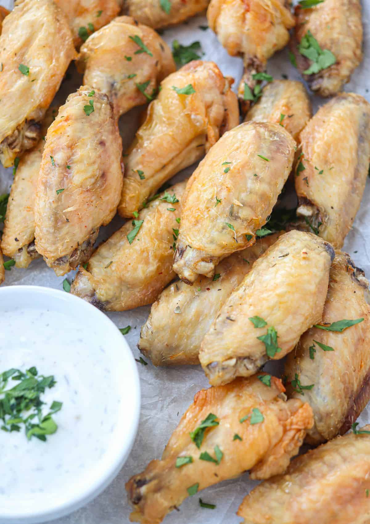 brined chicken wings browned and crispy stacked with a side of ranch dip.