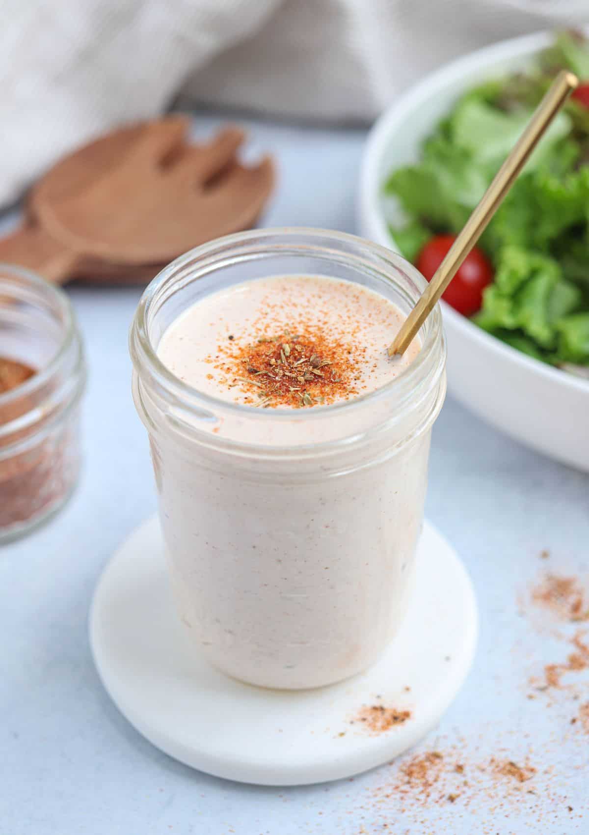 creamy cajun salad dressing in a glass jar with a gold soon inserted.