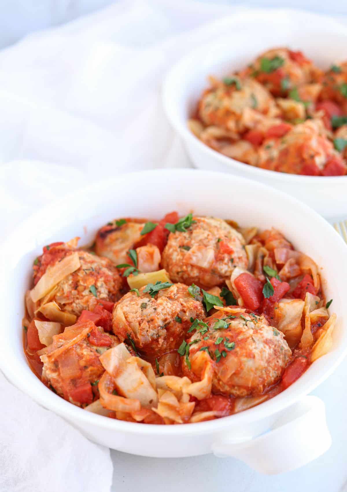 cabbage and meatballs in white bowls.