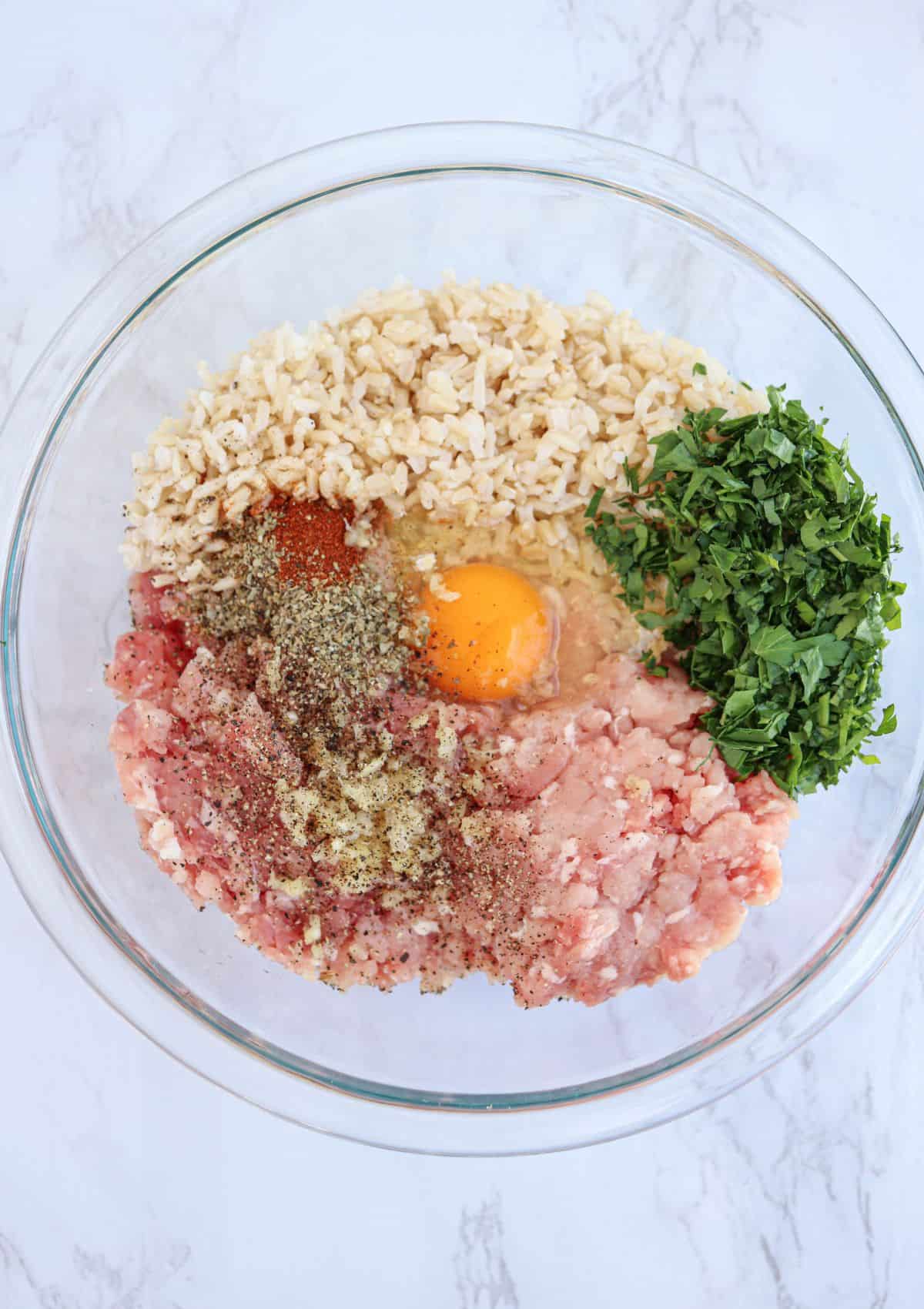 ground pork, ehh, spices and herbs in a glass bowl.