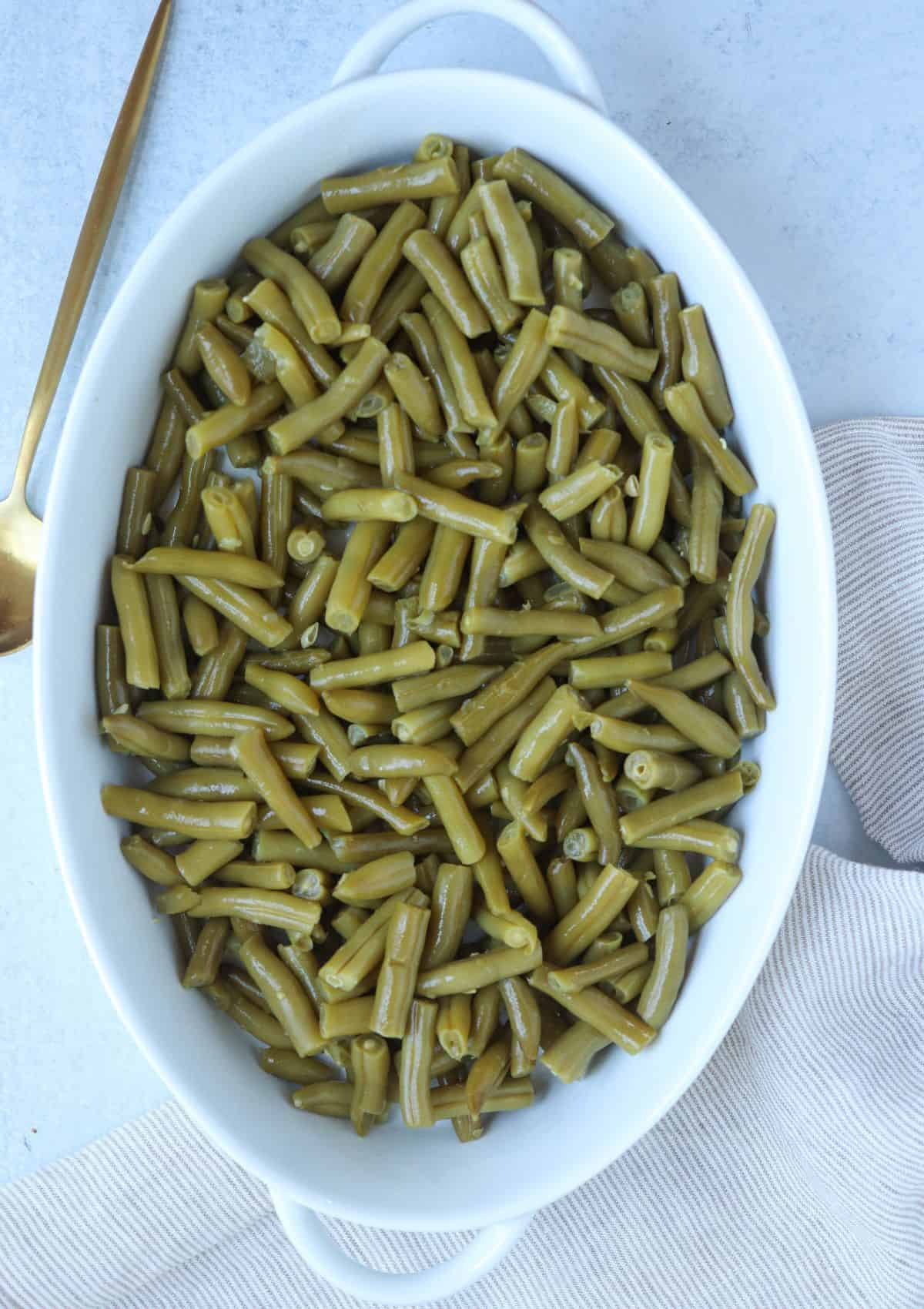 canned green beans in a white oval casserole dish.