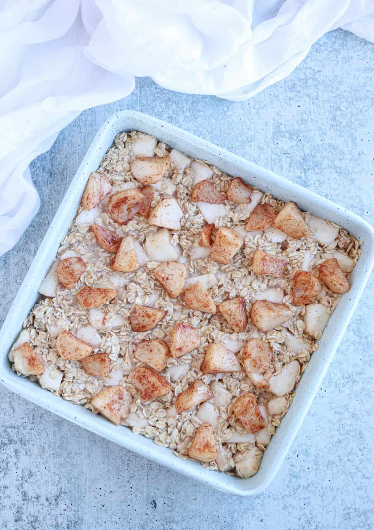 apple pie baked oatmeal in a teal square baking pan, before baking.