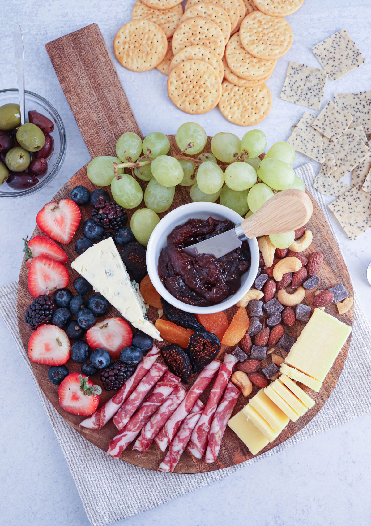 a small round charcuterie board with cheese, grapes, salami, nuts and fig spread.