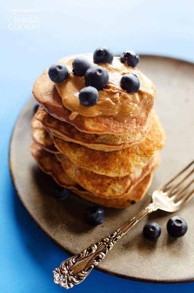 healthy banana pancake stack topped with nut butter and blueberries.