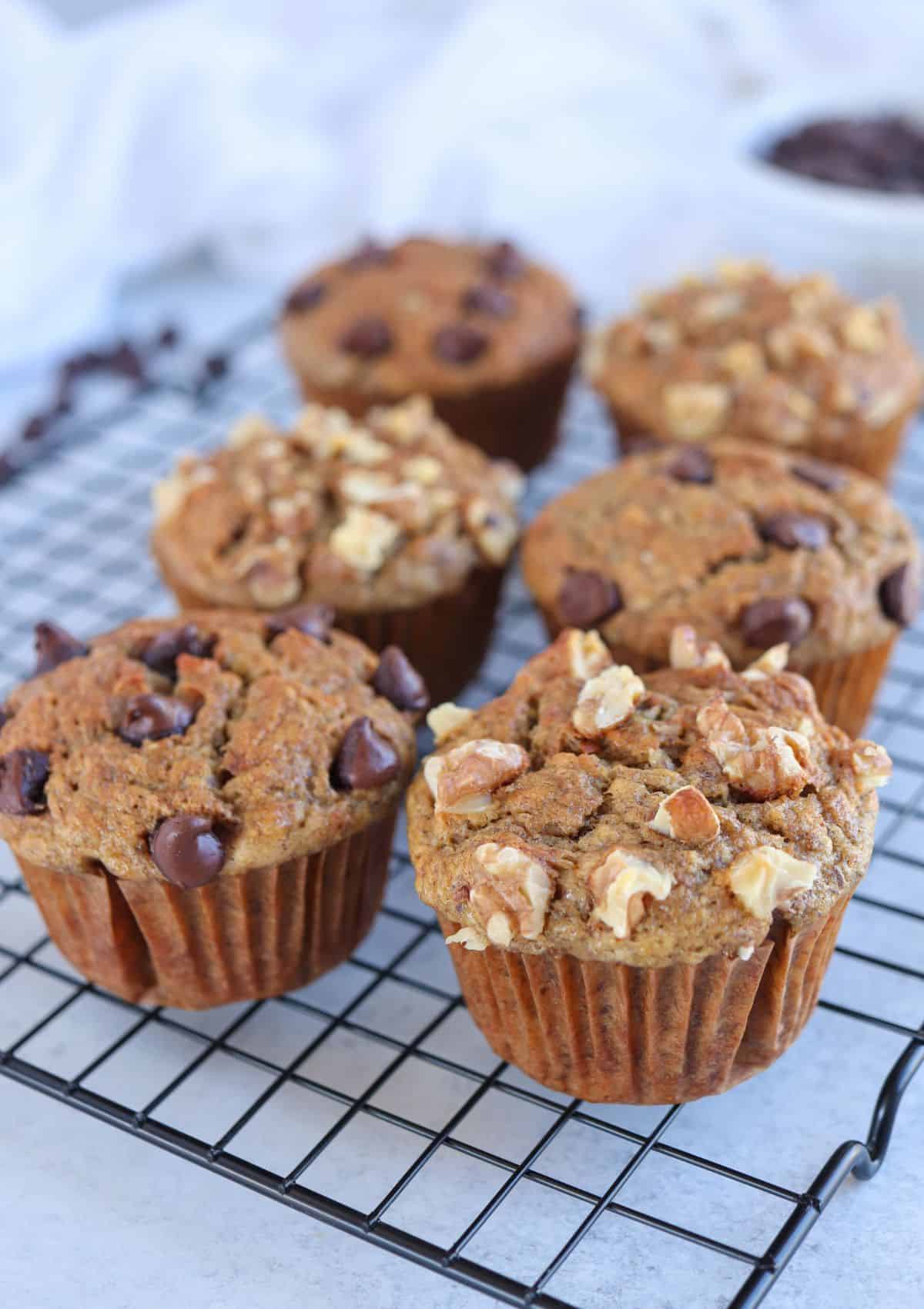 banana muffins with walnuts and chocolate chips on a black wire rack.