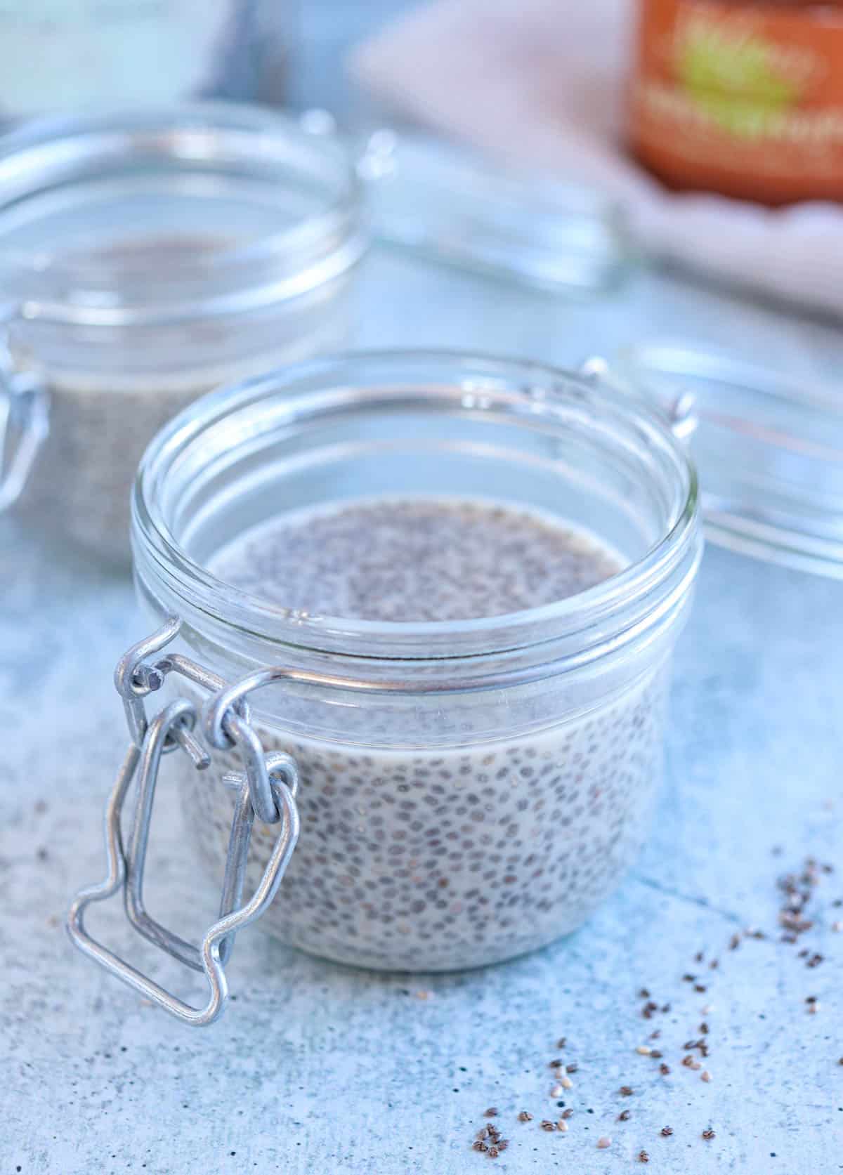 two glass jars with chia pudding on gray surface.