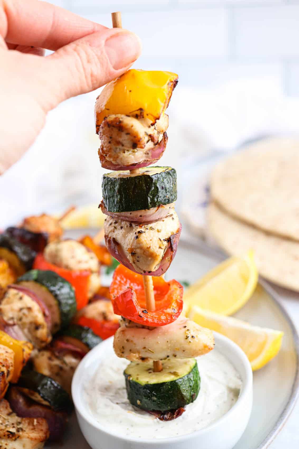 dipping a chicken and veggie skewer in ranch dip.