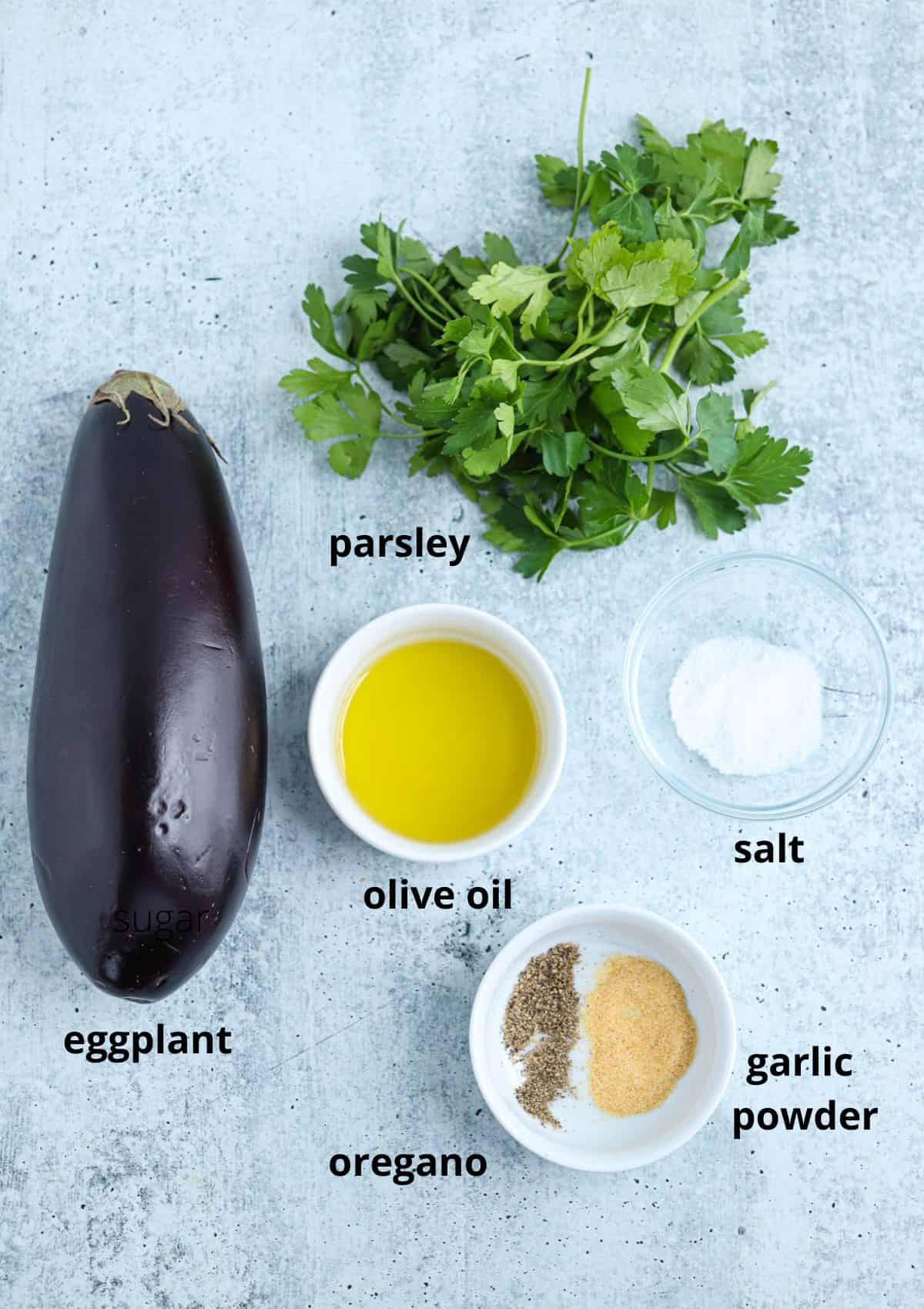 ingredients for making air fryer eggplant on gray surface with captions.