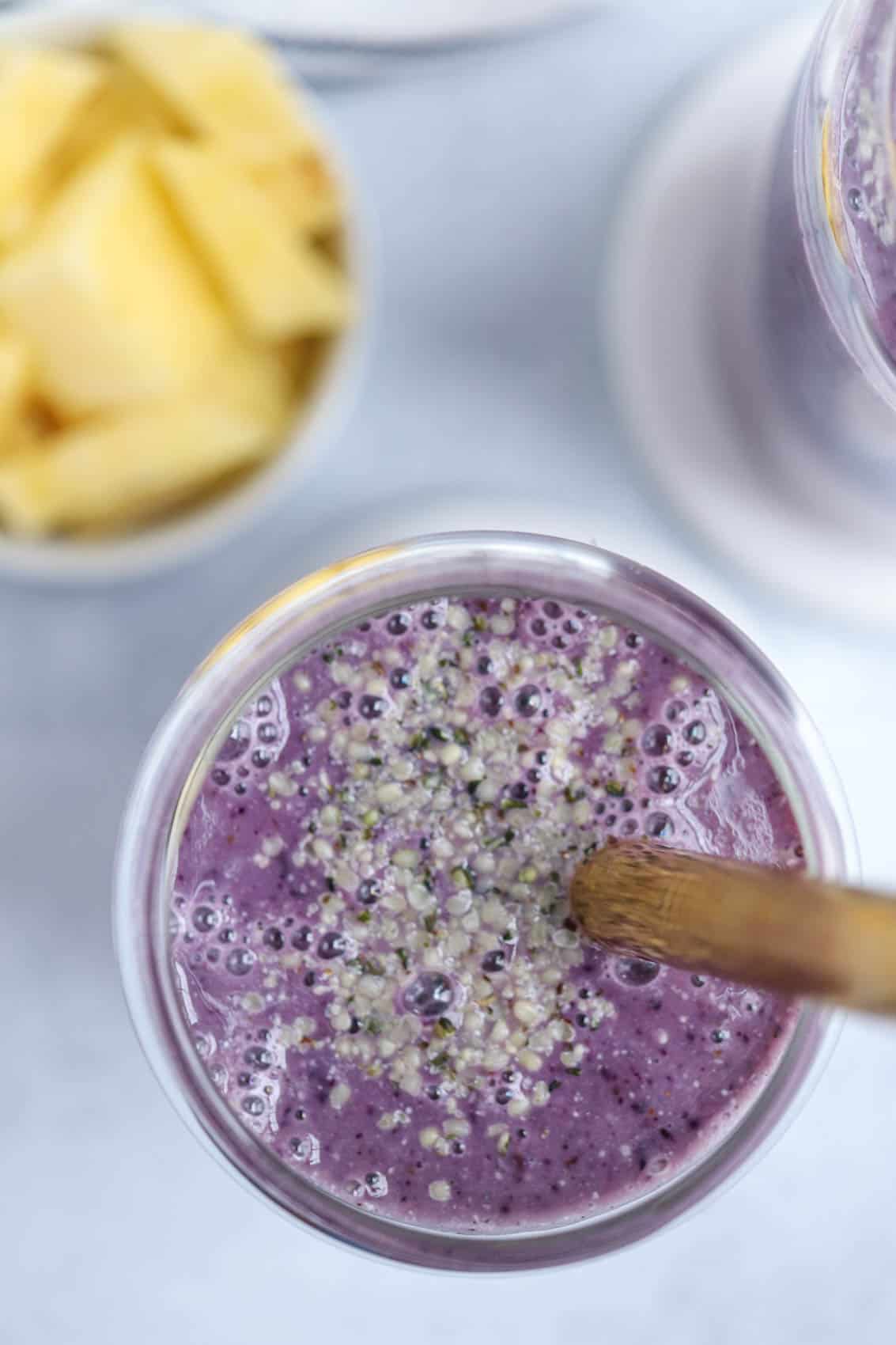 an overhead shot of a blueberry smoothie sprinkled with hemp hearts.