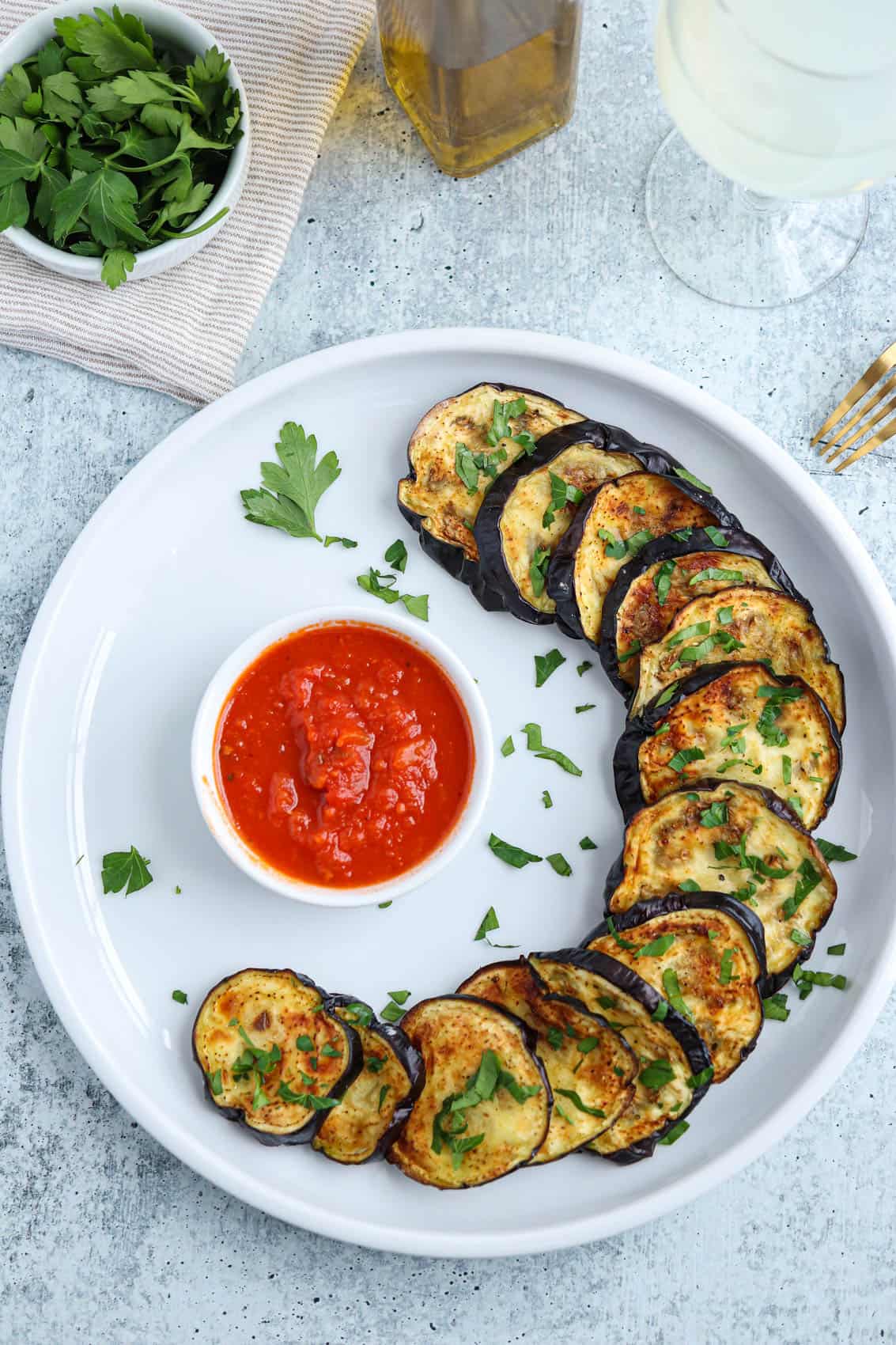 air fryer roasted eggplant slices on a white plate with a side of Marinara sauce.