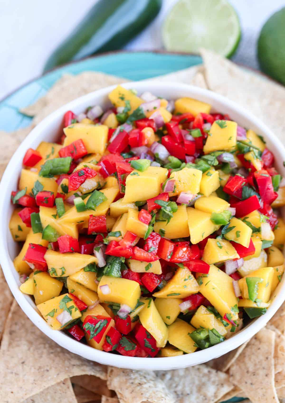 fresh mango salsa with red peppers, cilantro and jalapeno in a white bowl.