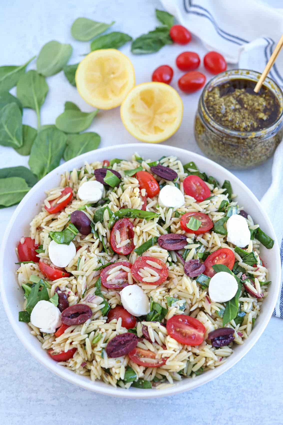 orzo pasta salad with spinach, olives, cherry tomatoes, mozzarella cheese and pesto.