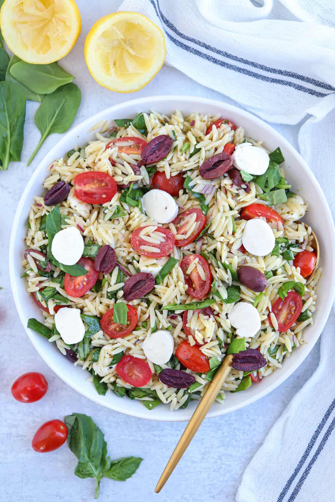orzo pasta salad with spinach, olives, cherry tomatoes, mozzarella cheese and pesto.