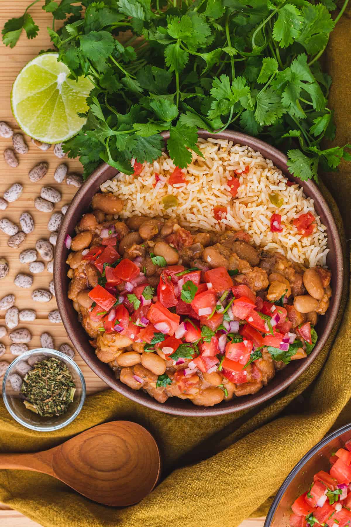 pinto beans and rice in a round brown bowl topped with pico de gallo.