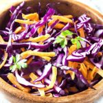 red cabbage and carrot slaw in a wooden bowl.